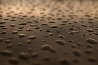 Macro water droplets on dark surface with golden light
