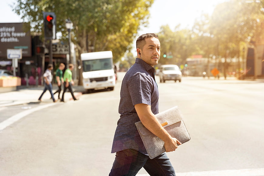 Businessman crossing street with laptop bag