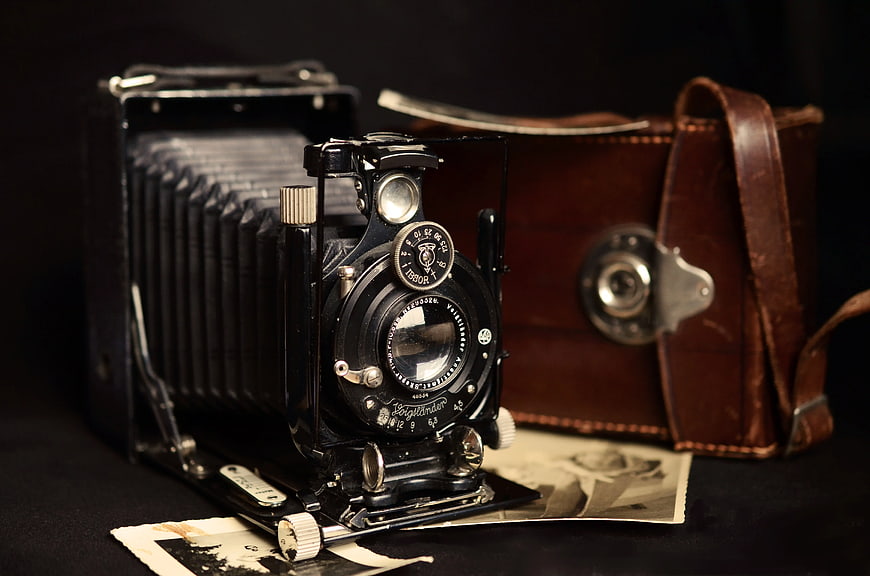 Vintage Black Folding Camera with Leather Case and Old Photos
