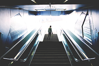 Man Walking Up Stairs Towards Bright Light in Modern Building