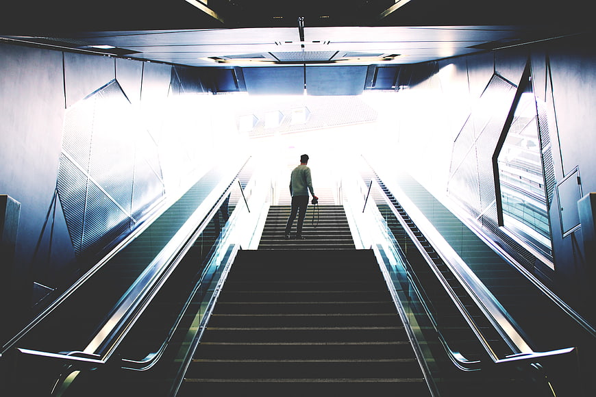 Man Walking Up Stairs Towards Bright Light in Modern Building