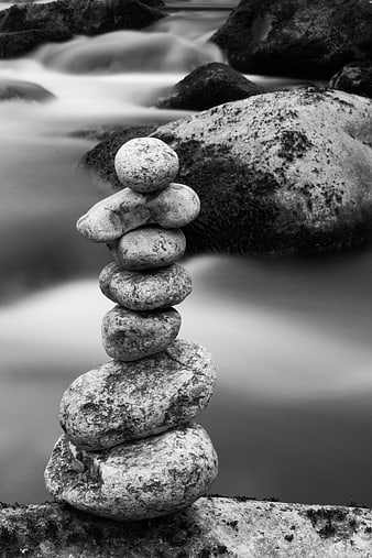 Black and white stacked river stones with long exposure water background
