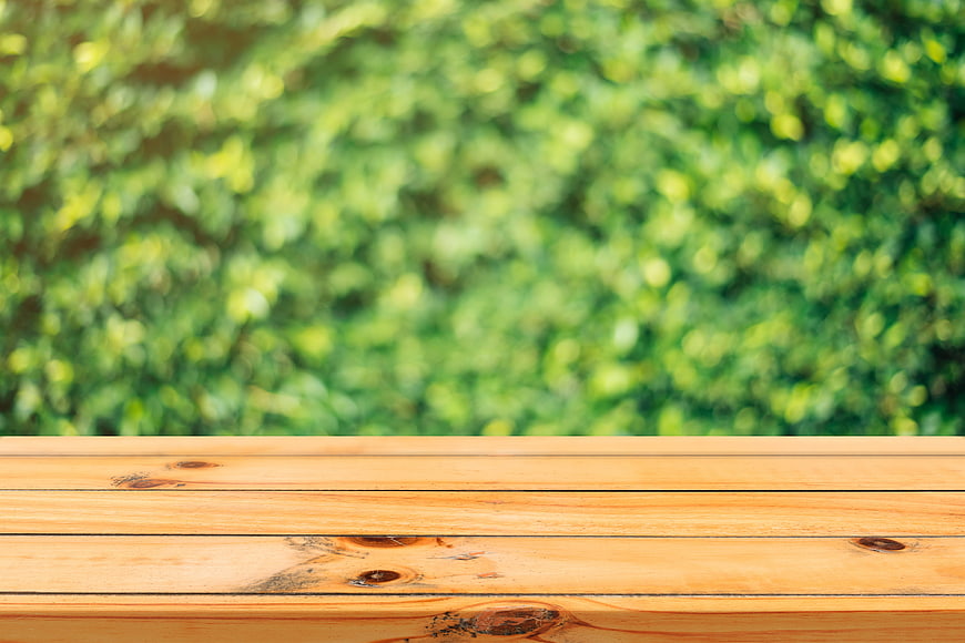 Empty wooden table surface with blurred green nature background