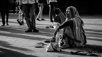 Black and white photo of homeless woman begging on street