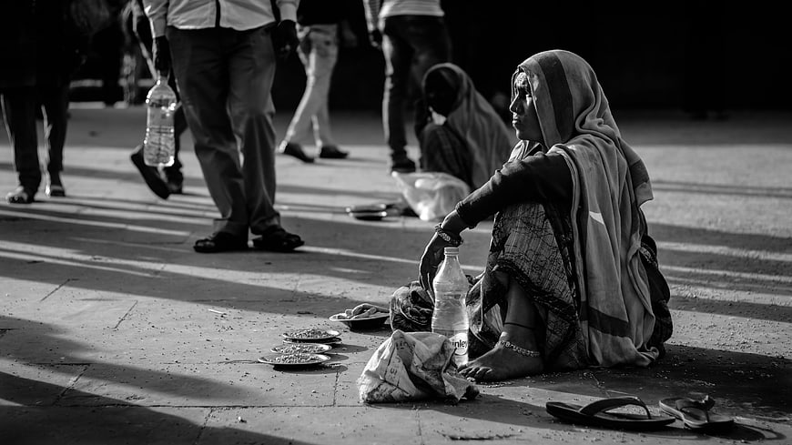 Black and white photo of homeless woman begging on street