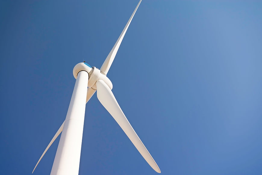 White Wind Turbine Blades Against Clear Blue Sky
