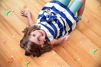Happy Girl Lying on Wooden Floor with Confetti