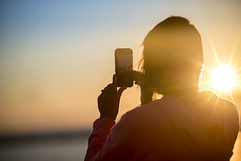 Woman Taking Photo of Sunset with Smartphone Silhouette
