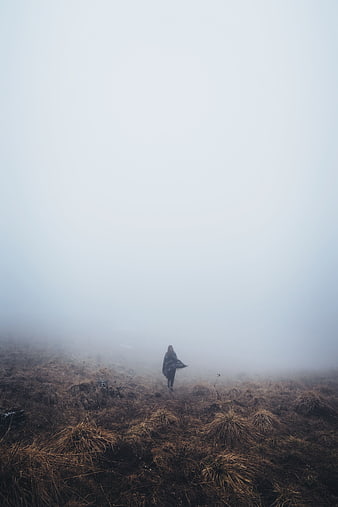 Woman walking alone in foggy highland landscape