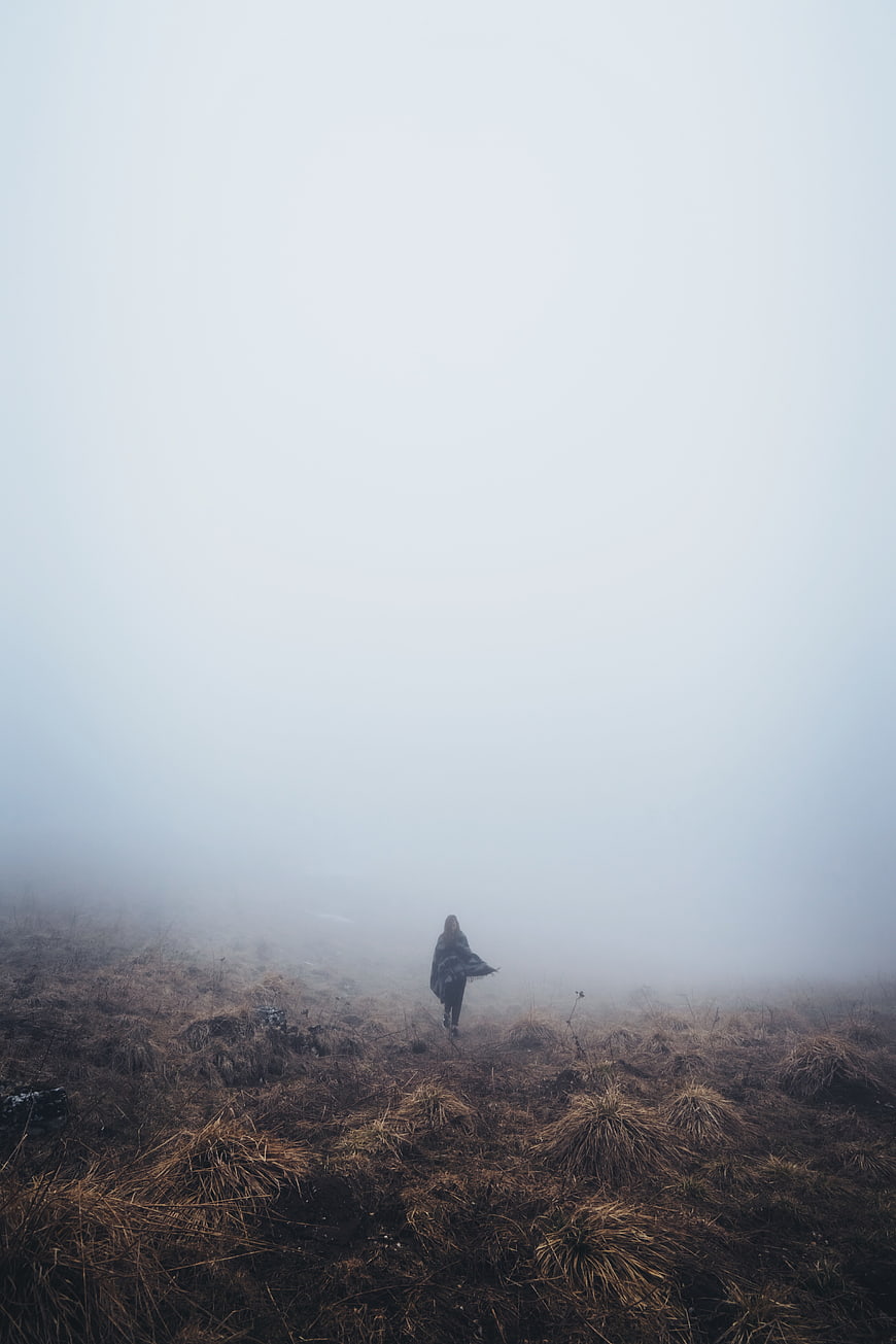 Woman walking alone in foggy highland landscape