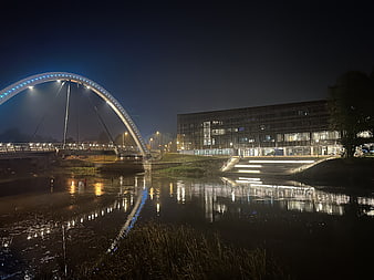 Modern Arch Bridge and Office Building at Night by River