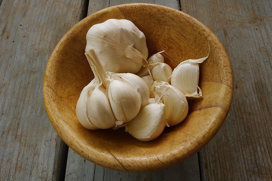 Fresh Garlic Bulbs in Rustic Wooden Bowl on Weathered Table