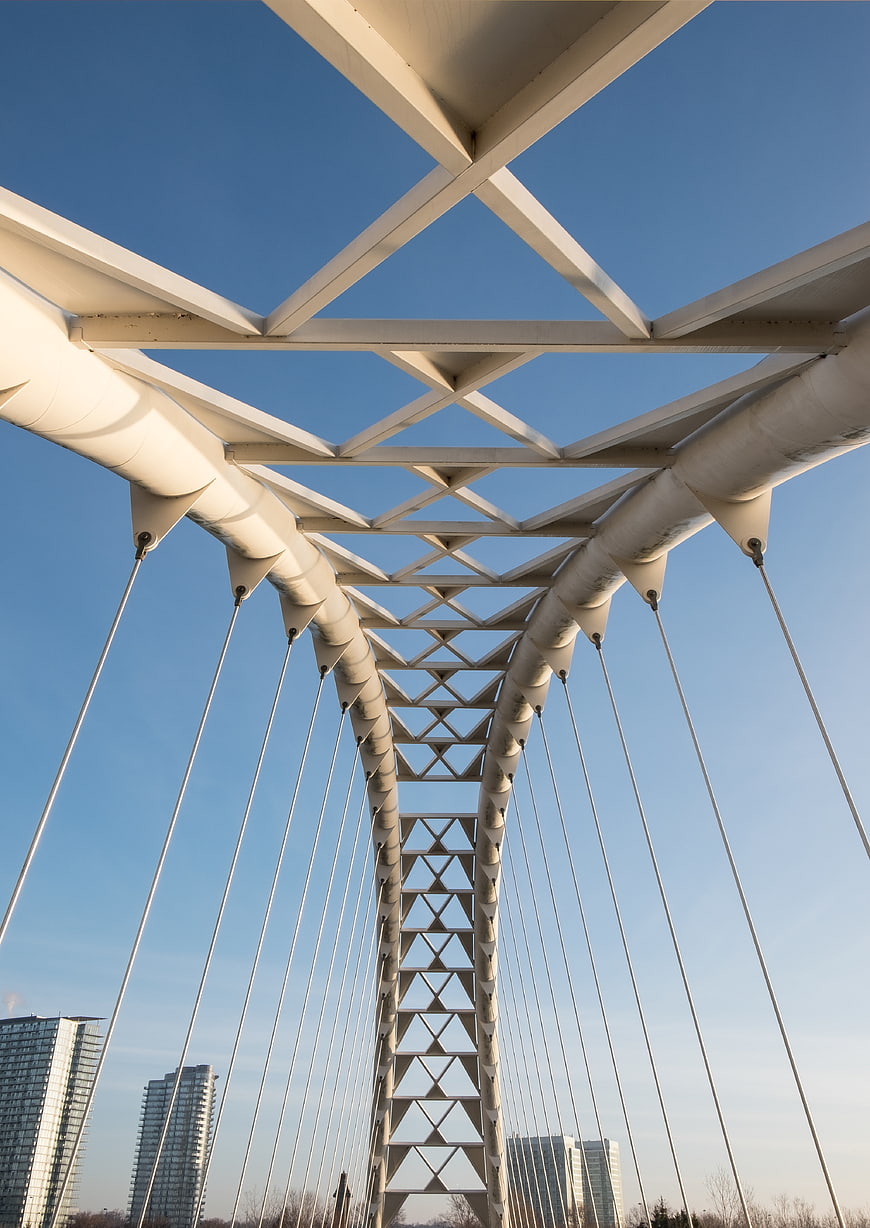 Low angle view of white cable-stayed bridge structure against blue sky