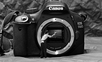 Miniature woman cleaning camera sensor inside DSLR body