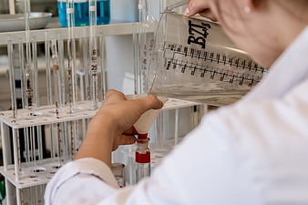 Scientist Pouring Liquid Into Test Tube In Laboratory