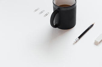 Minimalist black coffee mug and office supplies on white desk