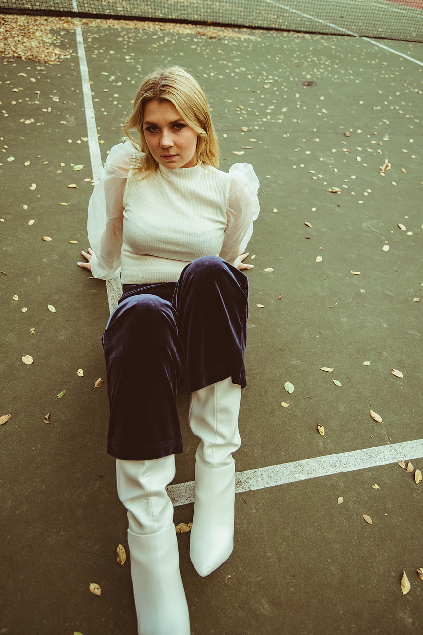 Blonde Woman in White Boots Sitting on Tennis Court