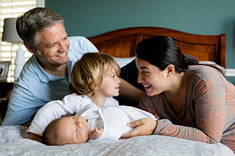 Happy family with newborn baby and toddler in bedroom