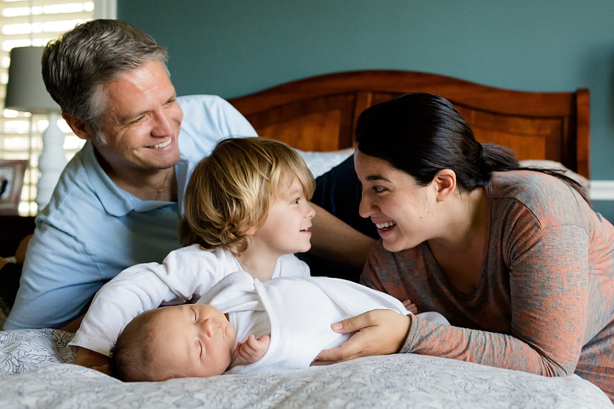 Happy family with newborn baby and toddler in bedroom