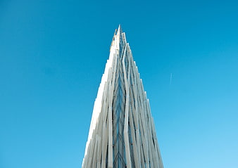 Low angle view of modern white skyscraper against blue sky