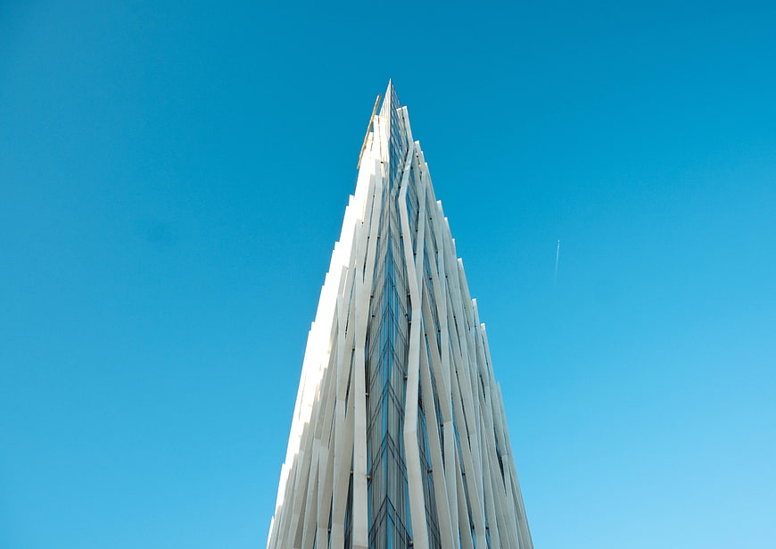 Low angle view of modern white skyscraper against blue sky