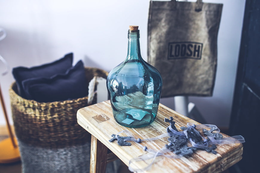 Blue glass carafe on rustic wooden stool with decorative crosses