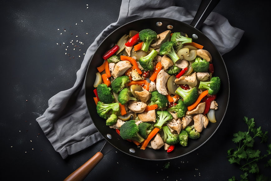 Top view of stir-fried chicken and broccoli in a skillet