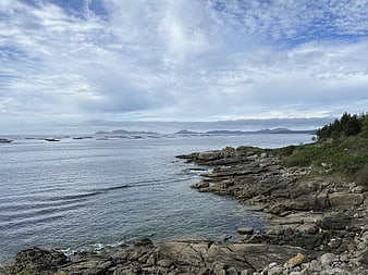 Rugged rocky coastline with calm sea and distant islands