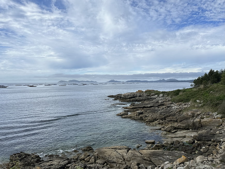 Rugged rocky coastline with calm sea and distant islands