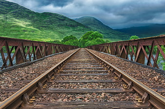 Rusted Railway Tracks on Bridge Leading to Green Scottish Highlands
