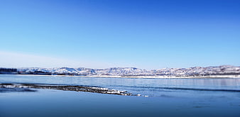 Serene Winter Landscape with Snowy Mountains and Blue Sky