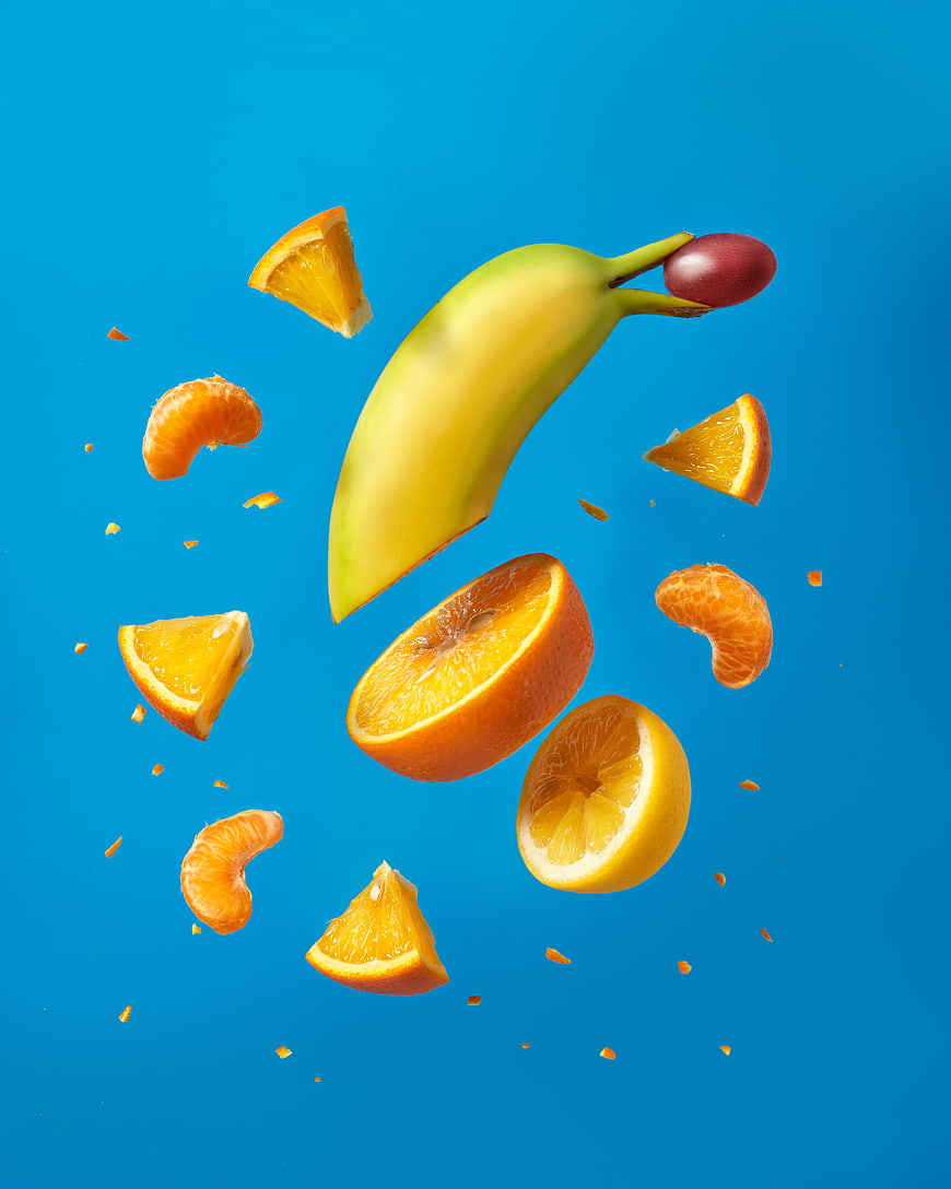 Fresh banana and citrus fruits floating on blue background