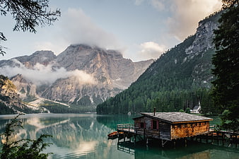 Serene Alpine Lake with Wooden Boathouse and Mountain Reflections