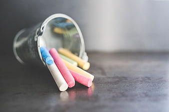 Colorful chalk sticks spilling from a metal bucket