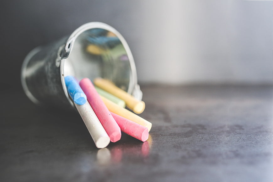 Colorful chalk sticks spilling from a metal bucket