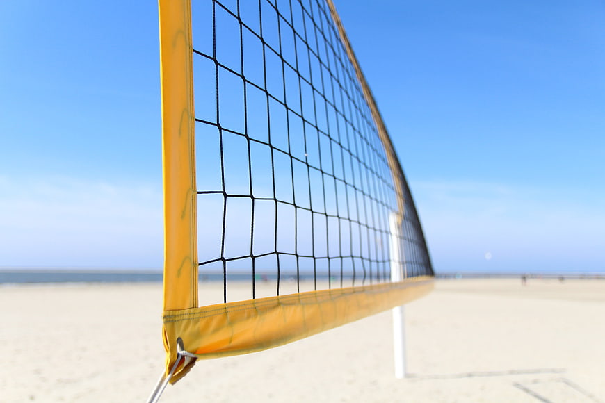 Close-up of yellow beach volleyball net on sandy shore