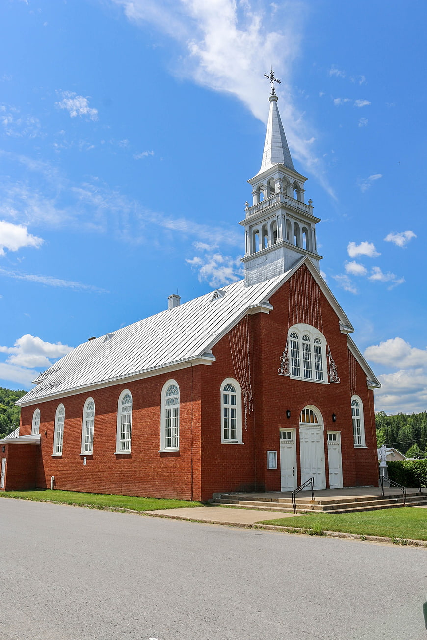 Red brick church with white steeple under blue sky