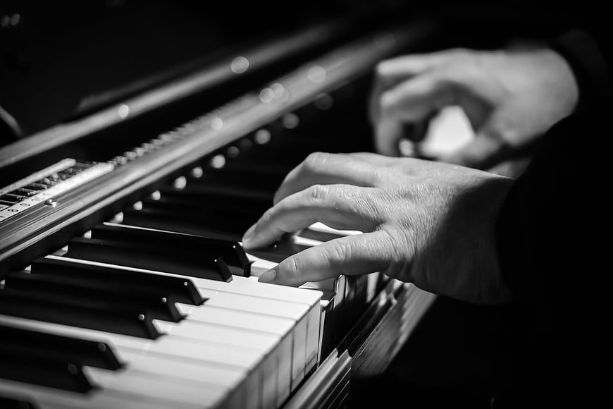 Close-up of hands playing piano keys in black and white