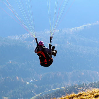 Paraglider flying over mountainous landscape in Austria