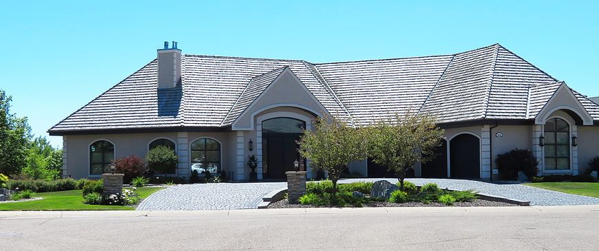 Luxury suburban home exterior with stone driveway and blue sky