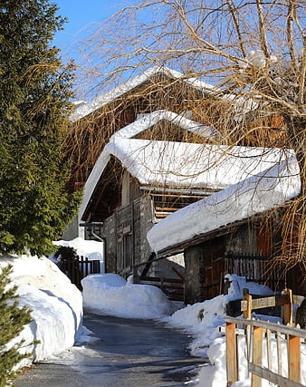 Rustic wooden chalet with snow-covered roof in winter