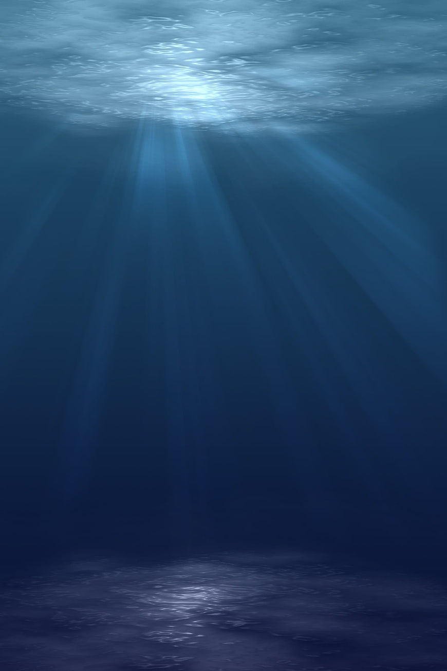 Deep blue underwater scene with sunbeams and ocean floor