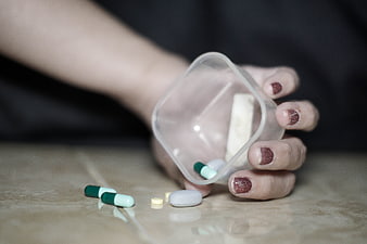 Hand Spilling Pills from Plastic Bottle on Floor