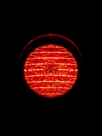 Close-up of glowing red traffic light lens at night