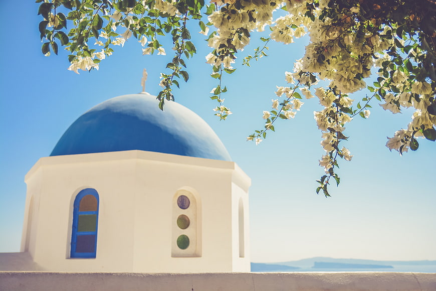 White church with blue dome and bougainvillea flowers