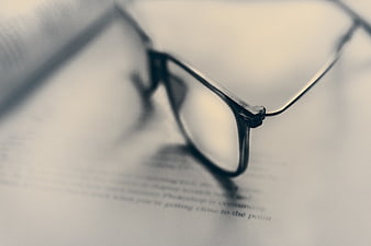 Close-up of black eyeglasses resting on an open book page