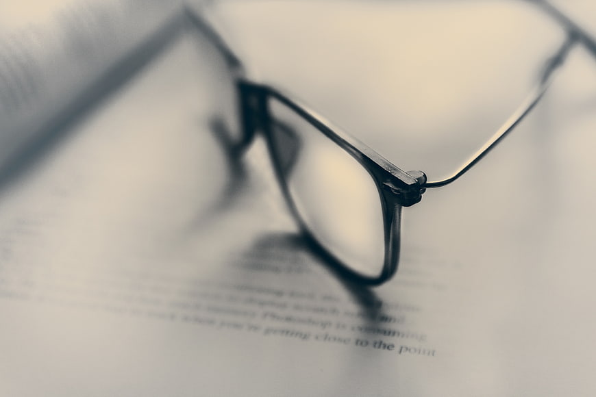 Close-up of black eyeglasses resting on an open book page