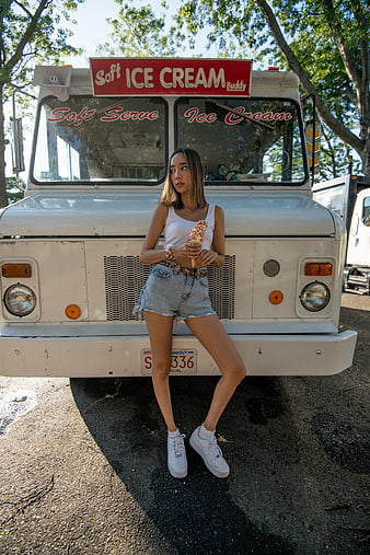 Woman eating ice cream cone in front of retro truck