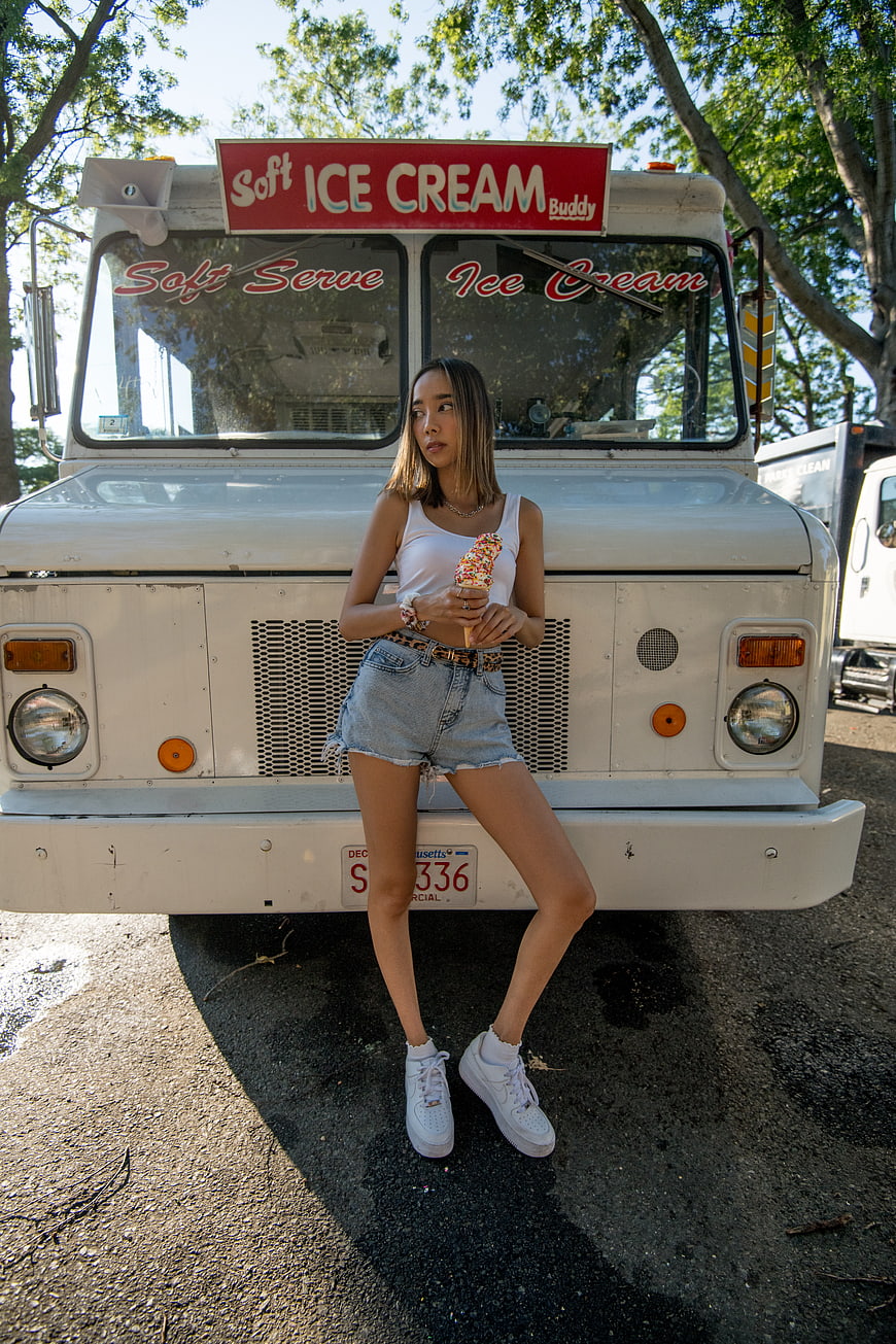 Woman eating ice cream cone in front of retro truck