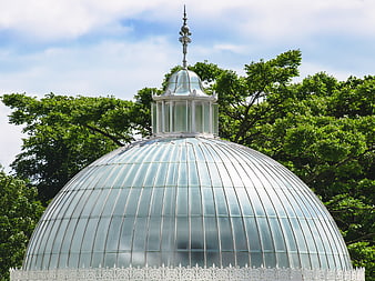 Glass Dome Conservatory with Ornate Spire Against Blue Sky